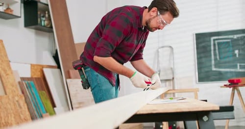Portrait of Hardworking Professional Carpenter Holding a Ruler and Pencil While Measuring a Board in