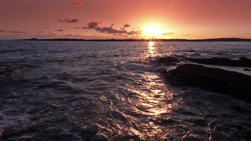 Cinémagraphe de vagues sur des rochers au coucher du soleil au Ralenti