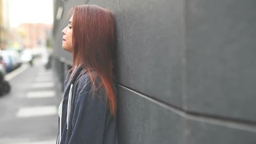 Woman Leaning Against Wall Gazing Upward Outdoors