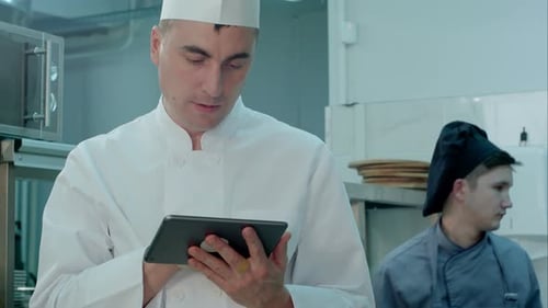 Chef Looking for Recipes on Digital Tablet in the Professional Kitchen