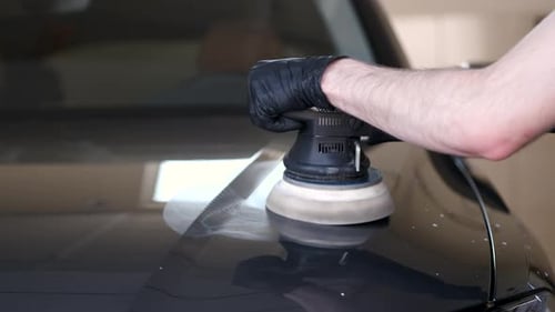 Man Polish a Car in a Garage