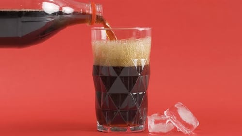 Dark Soda Drink Poured into Glass with Ice