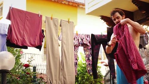 Shirtless Man Taking Clothes off Washing Line