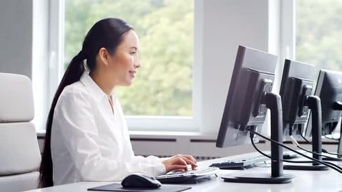 Mujer de negocios asiática trabaja en su mesa en una oficina moderna.