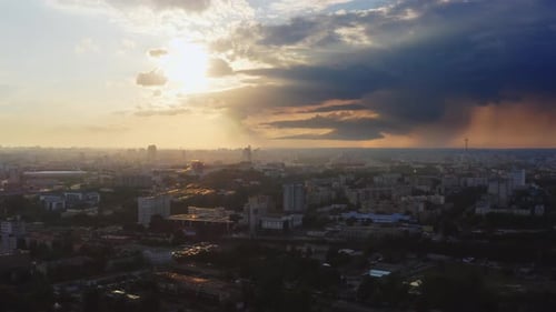 Paisagem industrial aérea. Voo sobre a cidade grande à noite. Nuvens tempestuosas na luz do pôr do sol. Chuva