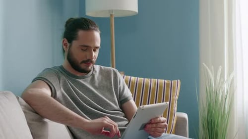 Man Relaxing on Couch Using Tablet