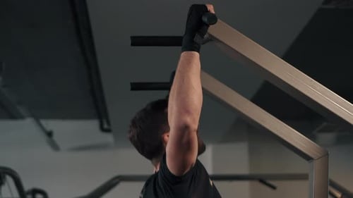 Male Athlete Pulls Himself Up on Horizontal Bar, Side View