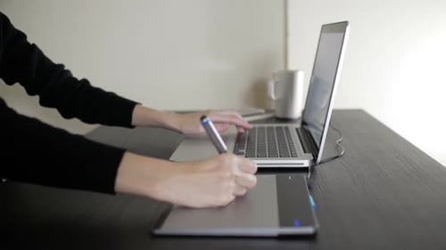 Woman Using Graphics Tablet While Working on Laptop