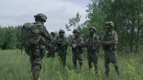 Soldiers in Camouflage with Assault Rifles in Field Commander Instructs the Soldiers Military Action