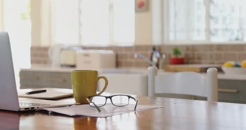 Laptop with documents, spectacle and coffee mug on a table 4k