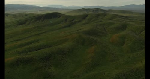 Helicopter aerial shot tracking down green fields, overcast day