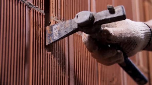 Worker hammering ceramic blocks