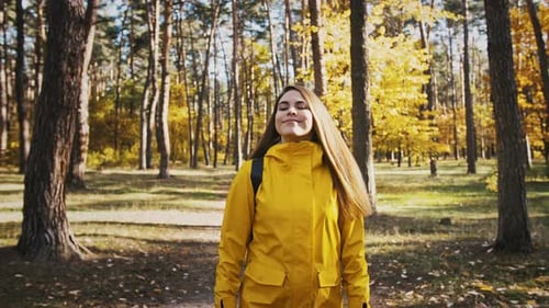 Young Female Smiling Taking a Deep Breath and Looking Around While Walking By Path in Autumn Wood on