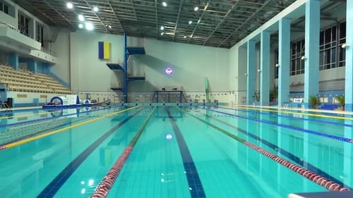 Ausschalten der Lichter im leeren Pool mit klarem Wasser und Trennschienen zum Schwimmen. Blaues Wasser in