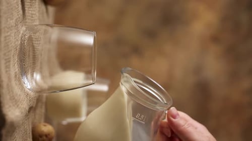 Hand Pouring Creamy Liquid Into Glass Still Life