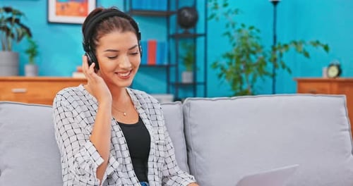 Woman Listening to Headphones Using Laptop at Home