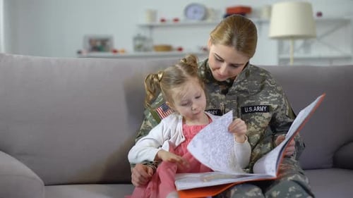 Military Woman Reading Book with Child at Home