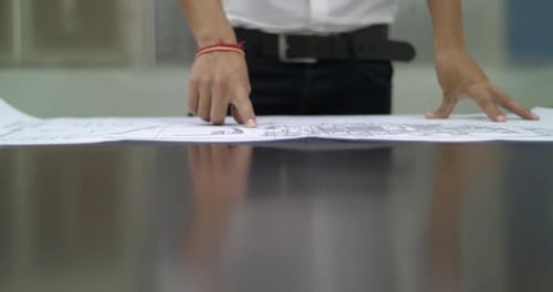 Man Unrolls Technical Drawing in Office Environment