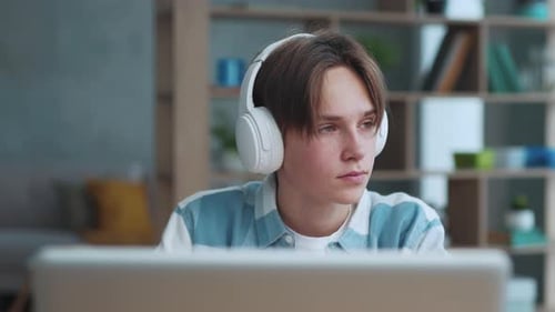 Smart Teenager Boy in Headphones Listening to Music at Home Close Up