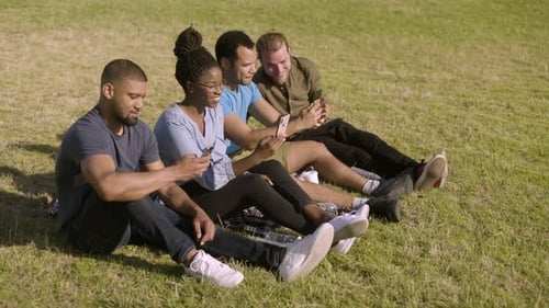 Friends Using Phones Together in the Park