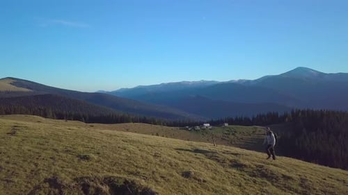 Person Hiking Across Mountain Hills Landscape