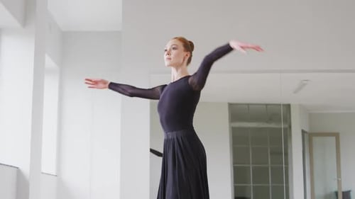 Caucasian female ballet dancer practicing ballet during a dance class in a bright studio