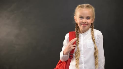 Smiling Girl with Backpack in Front of Chalkboard