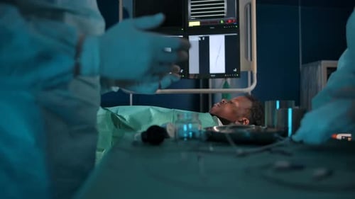 Darkskinned Patient on the Operating Table Against the Background of Surgeons' Hands