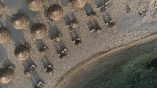 Aerial view above of empty beach with straw umbrellas on Achaia, Greece.