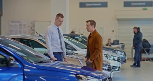 Car Dealership Consultant Shows a New Car Model to a Buyer