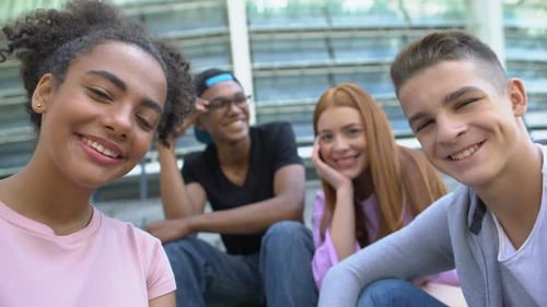 Smiling Teens Sitting Together Outside a Building
