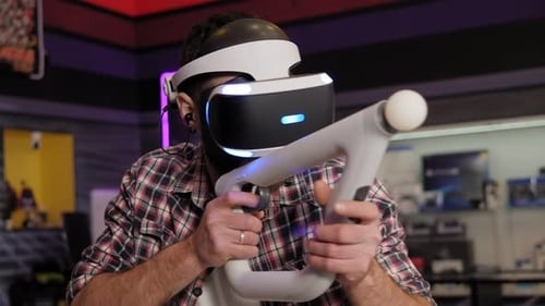 Un joven barbudo juega a videojuegos con un casco de realidad virtual
