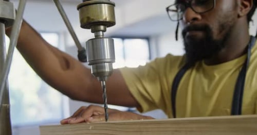 Carpenter drilling wooden plank with machine in workshop 4k