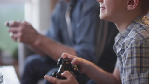 Boy and Adult Playing Video Games Together at Home