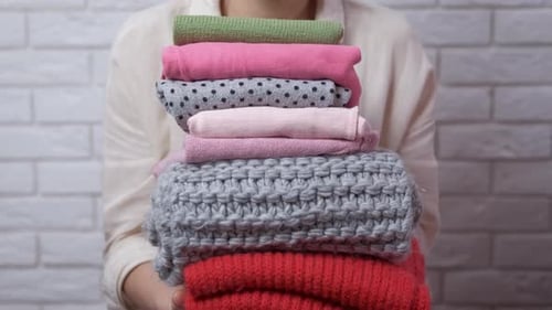 Woman Holding Stack of Folded Colorful Clothing