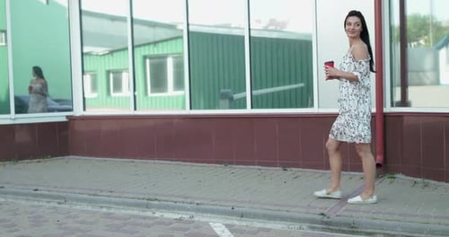 Happy Lady with a Cup of Beverage Walks at Office Centre Turns and Rejoices