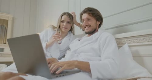 Couple Celebrating with Laptop and Champagne in Bed