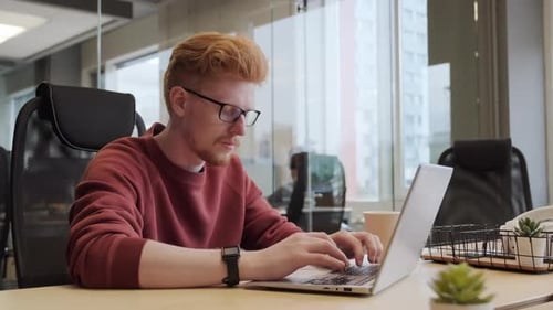Male Office Worker Typing On Laptop