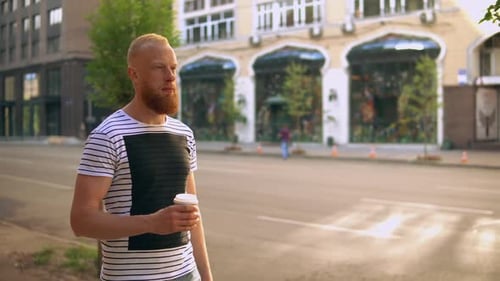 Bearded Man Walks with Coffee in City