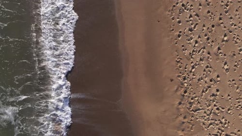 Aerial view of sandy beach and sea with waves