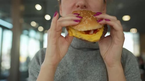 Woman Eating Hamburger and Fries in a Cafe Closeup