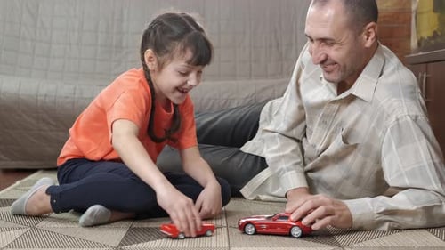 Girl and Man Playing with Toy Cars at Home