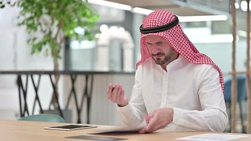 Man Reviewing Documents at Desk, Upset