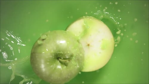 Green Apple Falling on Juice with Splash and Divided in Half