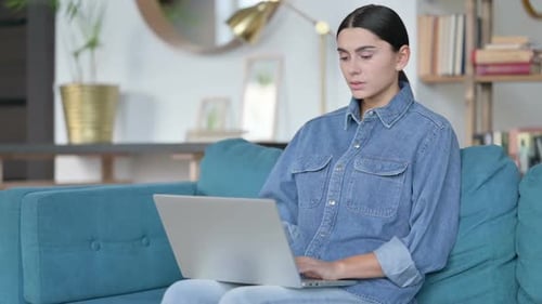 Woman Massaging Neck While Using Laptop on Couch
