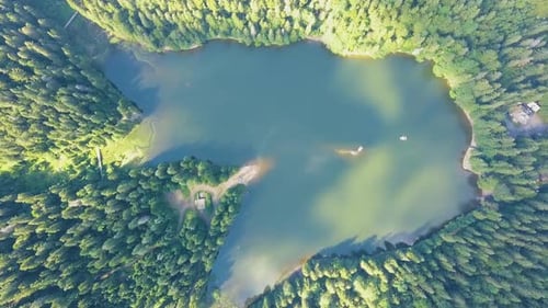 Top down aerial view of big lake with clear blue water between high mountain hills covered