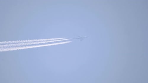 Airplane Flying with Contrails Across Blue Sky