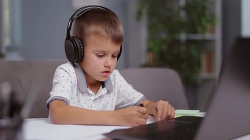 Boy with Headphones Drawing While Looking at Laptop