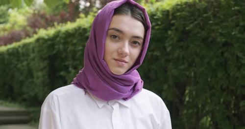 Schöne junge Frau blickt in die Kamera und trägt ein traditionelles Kopftuch. Attraktive Frau im Hijab