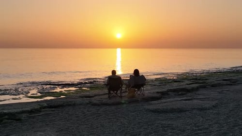 People sit on the beach and watch the sunset